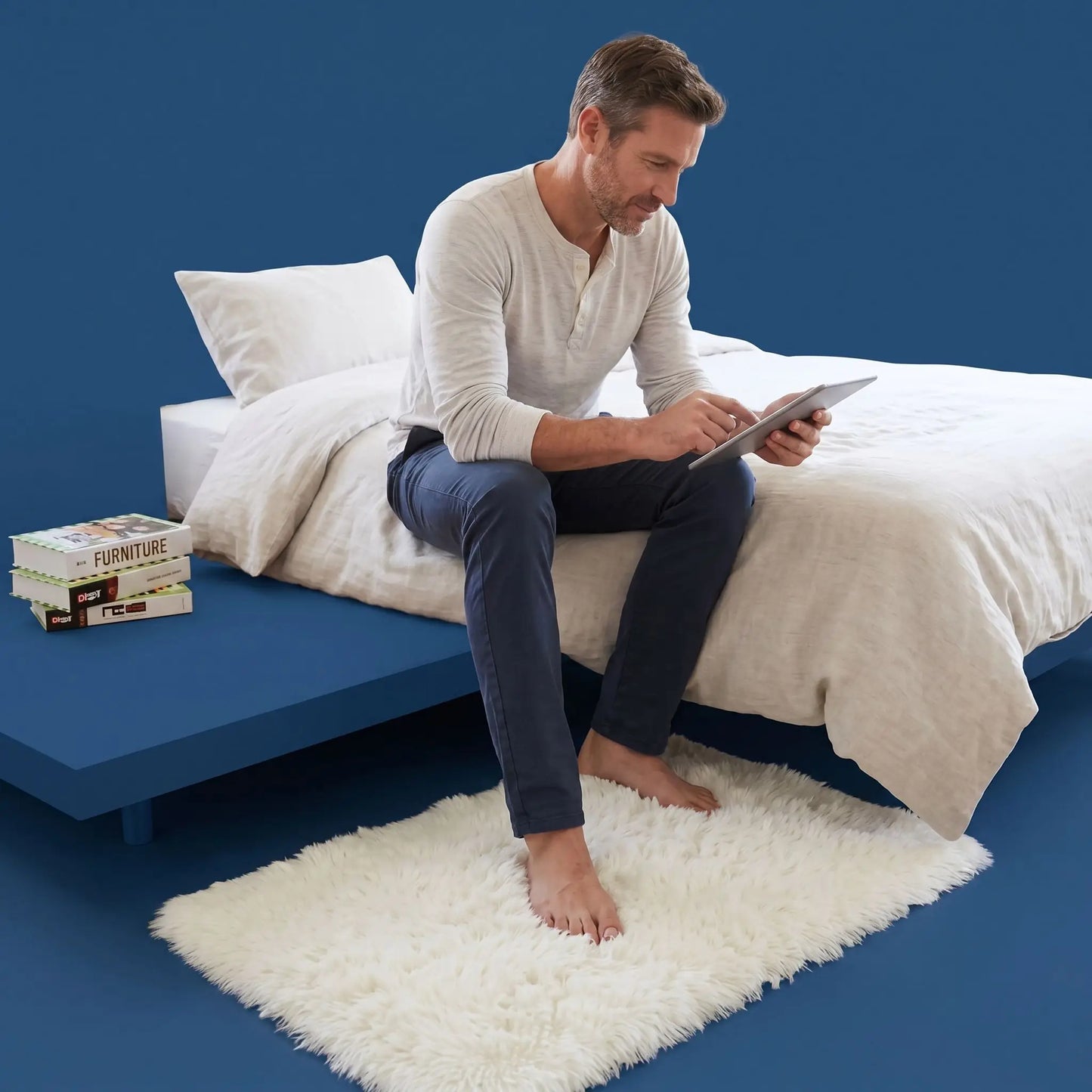 Homme avec tablette sur tapis descente de lit blanc