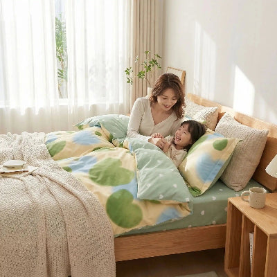 Femme avec fillette souriantes sous housse de couette douceur