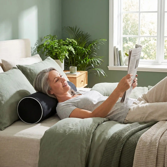 Femme avec journal couchée sur oreiller cervical noir