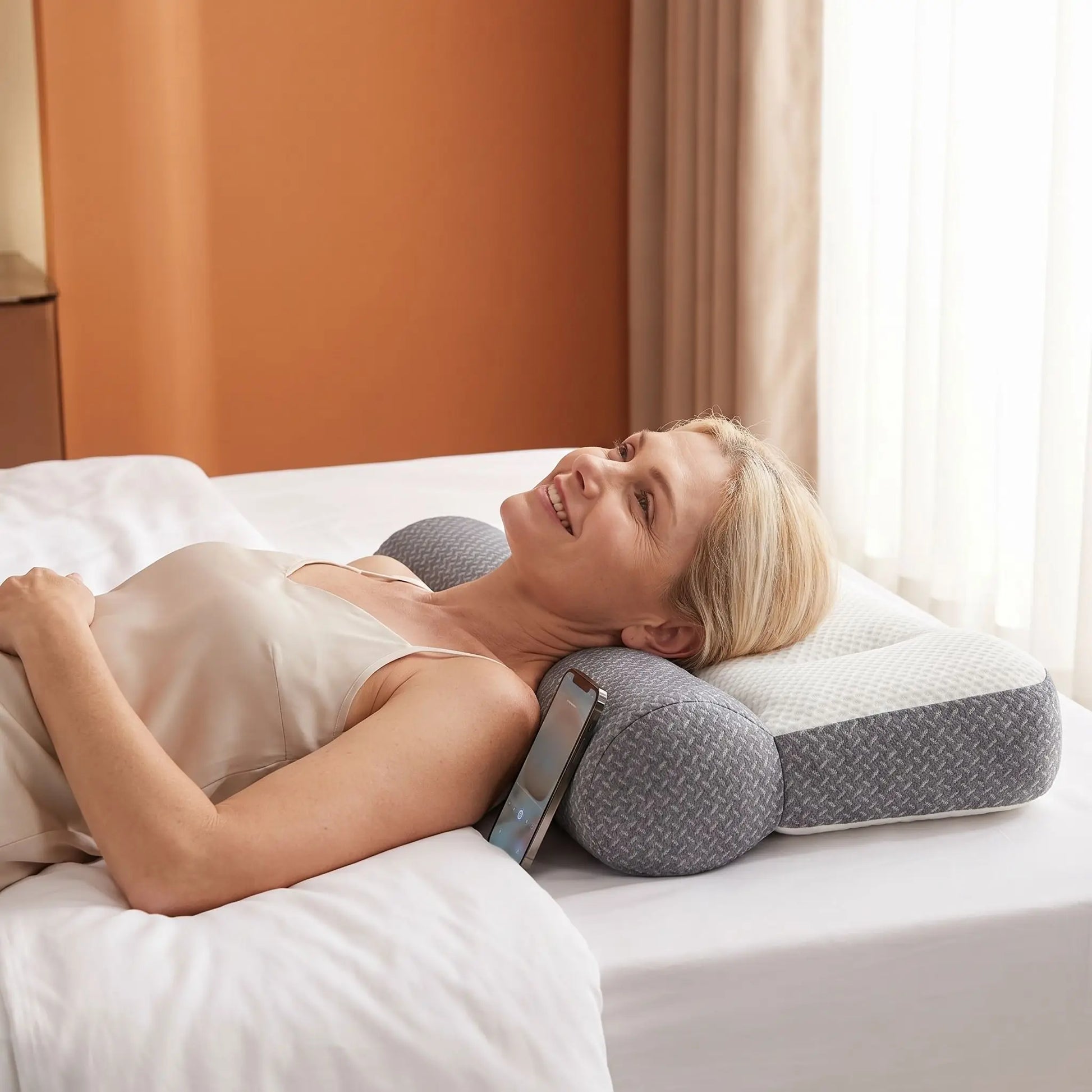 Femme couchée souriante tête sur oreiller cervical ErgoNuit.