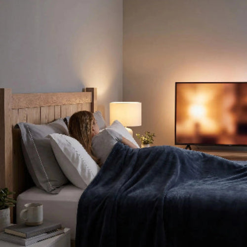 Femme regarde télévision sous couverture grise