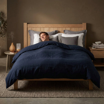 Homme dort sous couverture grise tête sur taies d'oreiller