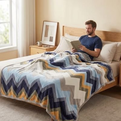 Homme lit livre sous couverture chevron ™