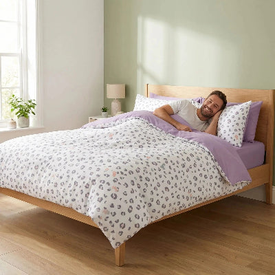 Homme souriant sous housse de couette violette