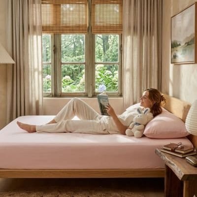 femme couchée dos lit sur draps housse rose poudré 