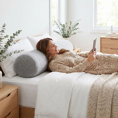  femme sur lit sourit avec taie traversin grise 