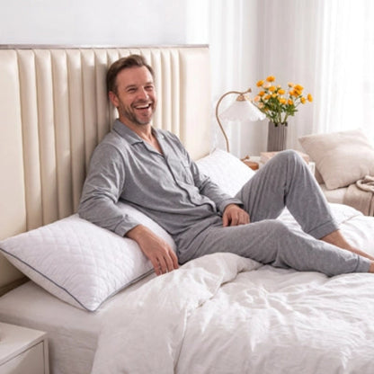 homme souriant assis sur lit adossé sur traversin en 180 blanc