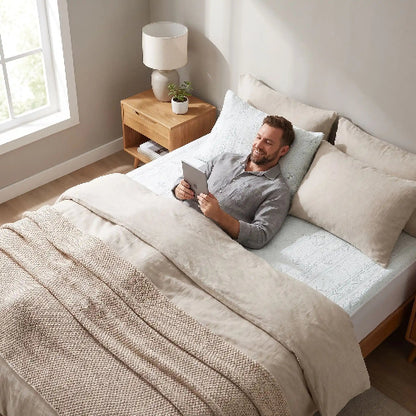 homme souriant couché sur drap housse frais gris sur dos avec tablette